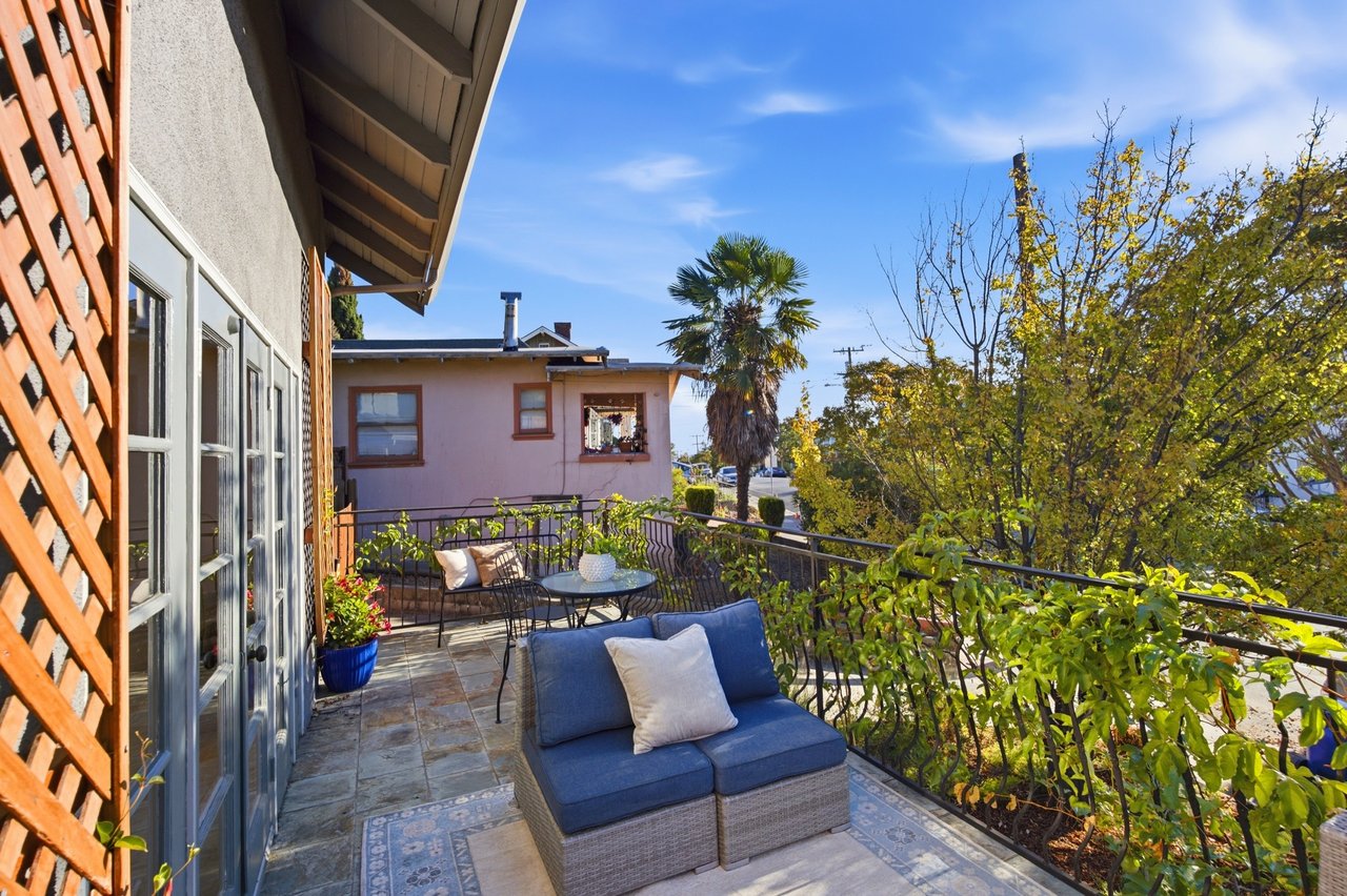 Furnished patio with blue outdoor seating, patterned tile, and leafy vines along the railing.