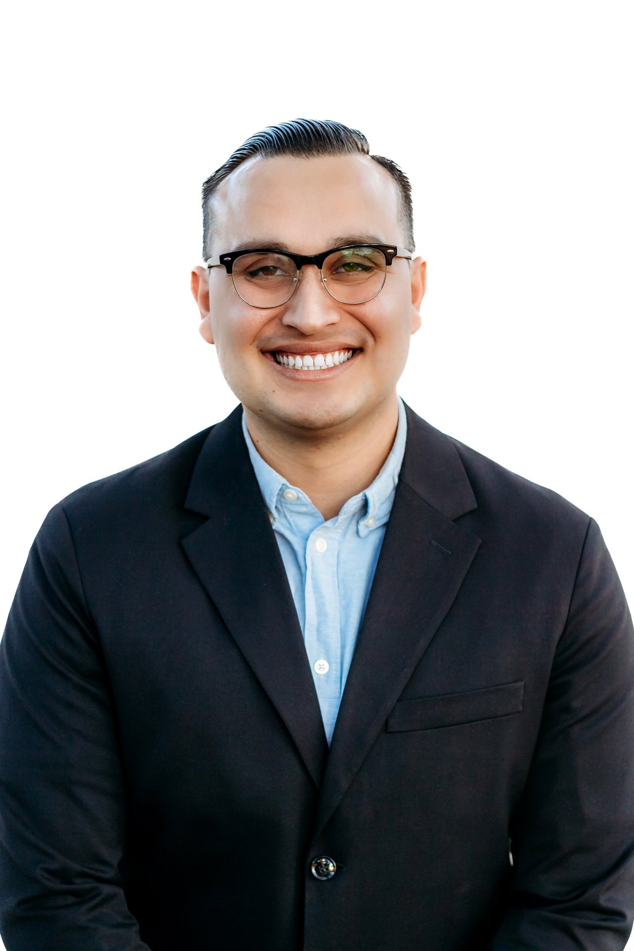 Professional headshot of Caleb Rivera, wearing a blue shirt and black blazer, smiling against a clean white background.