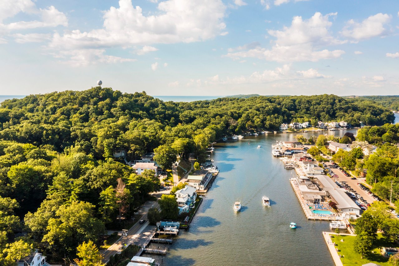 Aerial view of downtown Saugatuck, Michigan with boats on the Kalamazoo River and Mount Baldhead in the background.