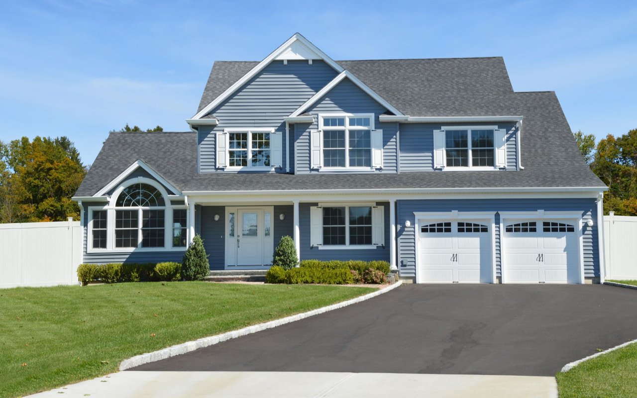 Blue two-story house with white trim, arched windows, and a double garage.