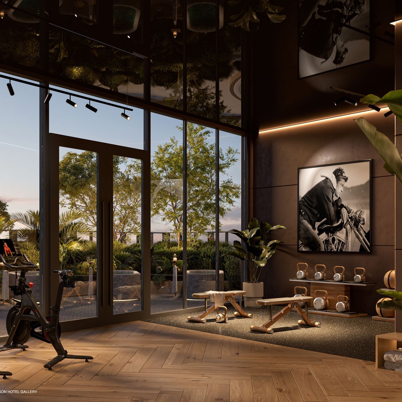 Fitness center with exercise bikes, kettlebells and dumbbells beside floor-to-ceiling windows overlooking greenery.