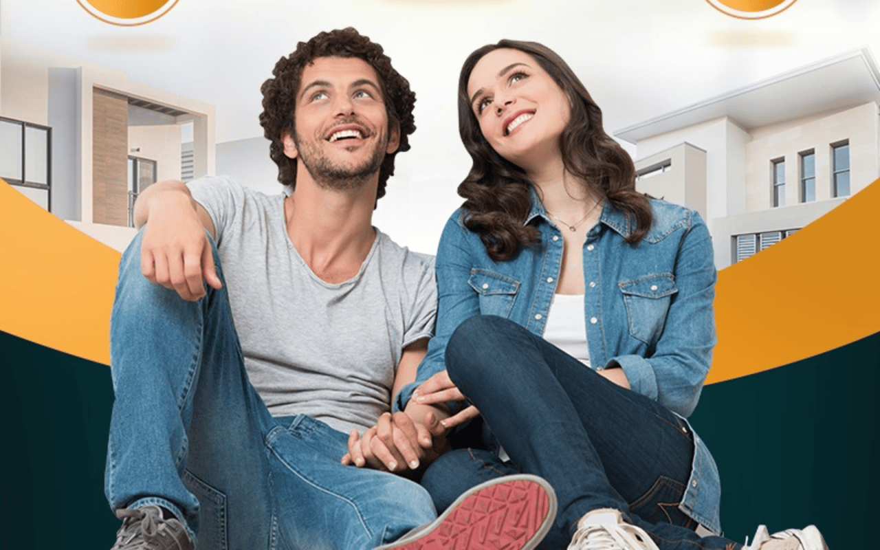Smiling couple sitting together in front of modern homes.