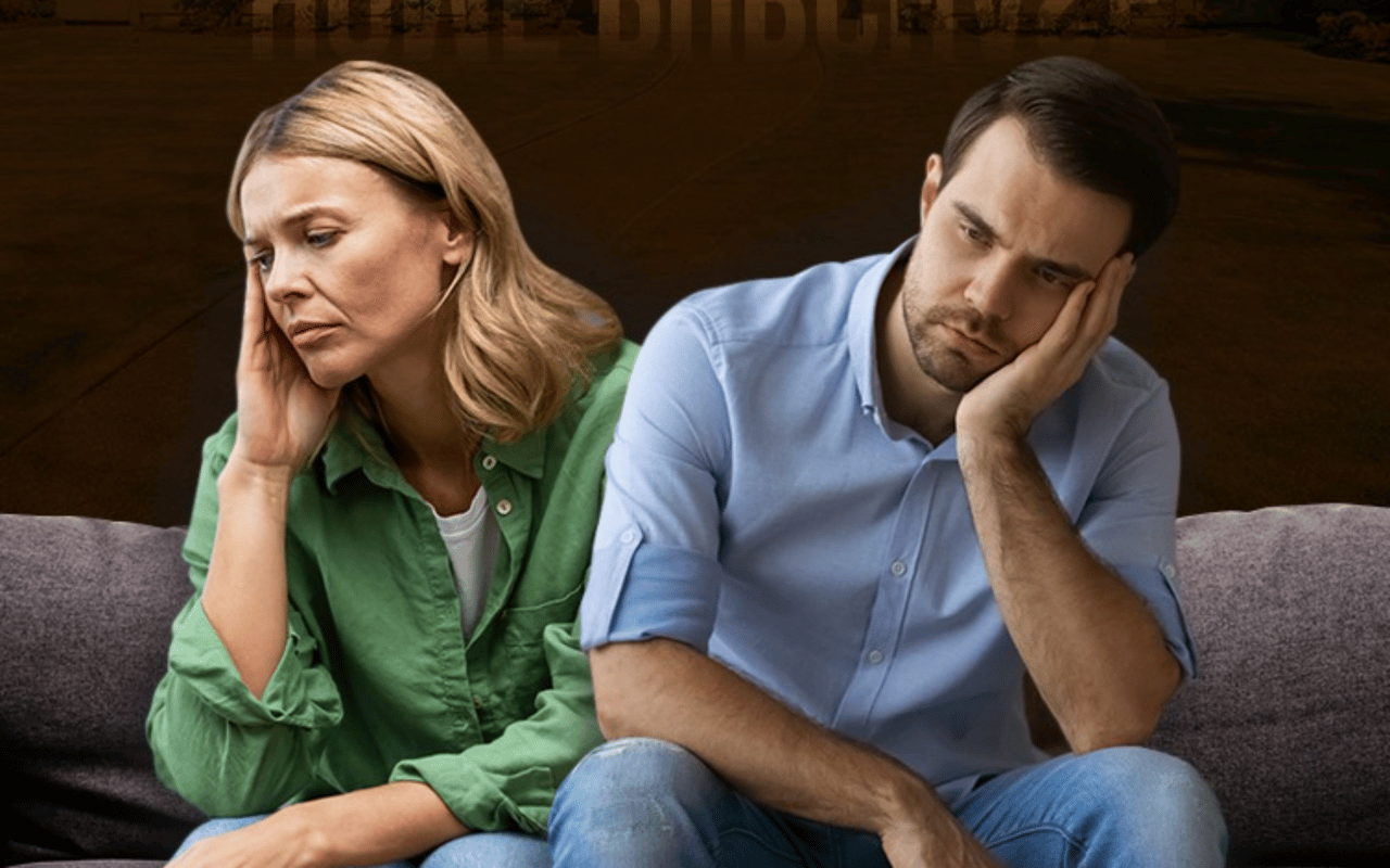 Worried couple sitting apart on a sofa, each resting their head in a hand.