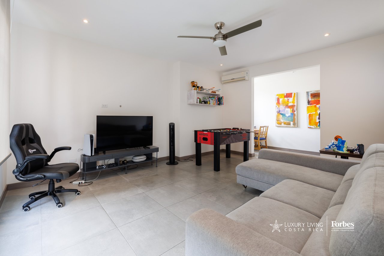 Townhouse living room with gray sectional sofa, tiled floor, television, and foosball table.