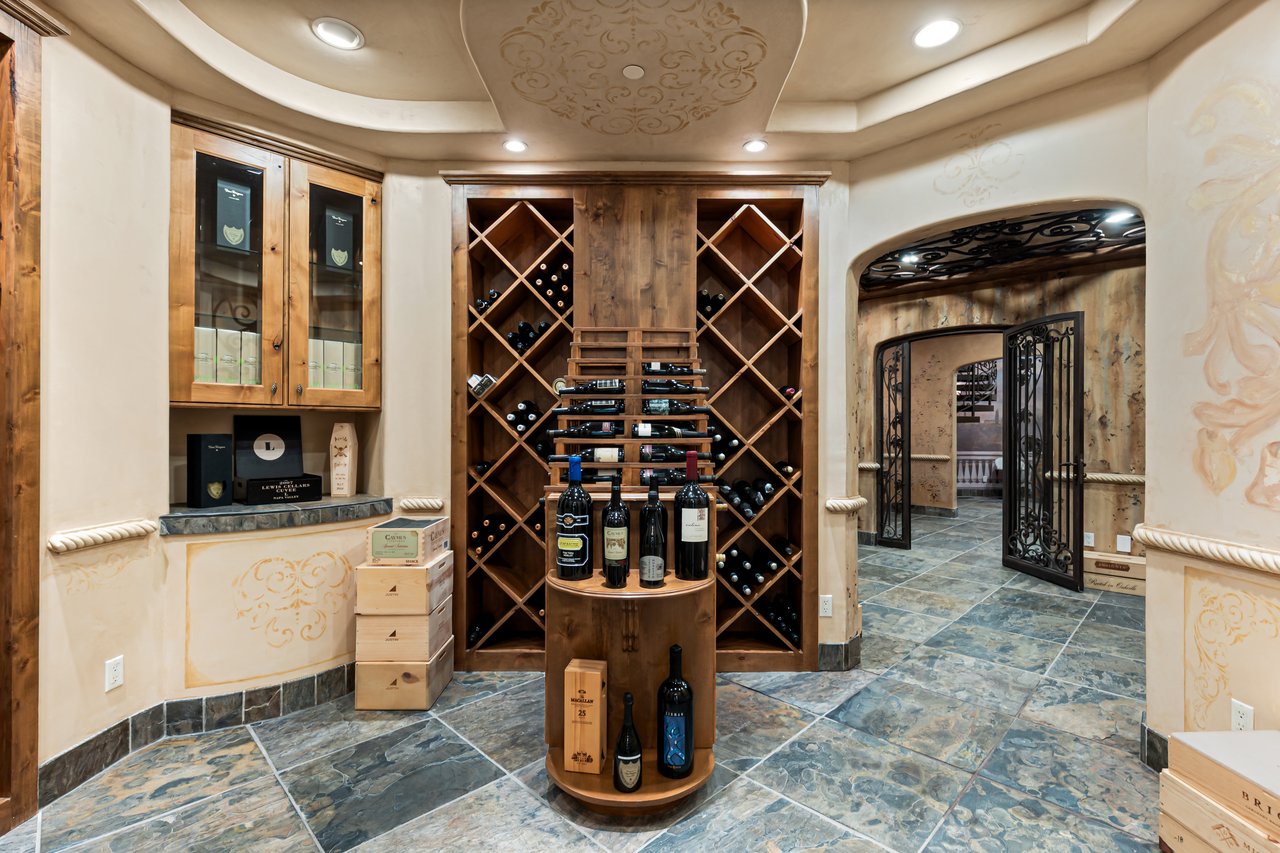 Wine cellar with wooden bottle racks, glass-front cabinets, and a central wine display.