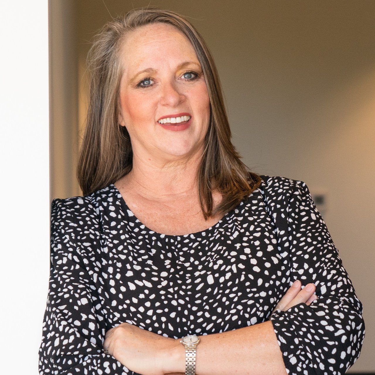 Dana Considine smiles with her arms crossed in a black-and-white patterned top.