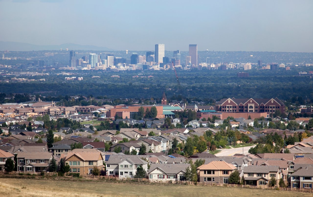 Denver skyline and residential neighborhoods with the Rocky Mountains in the background during spring, representing the May 2026 Denver Metro real estate market.