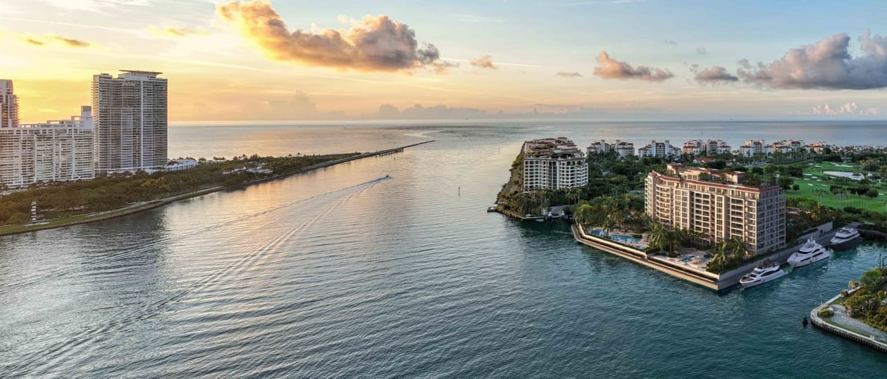 Waterfront condominiums and marina on Fisher Island beside a channel at sunset.