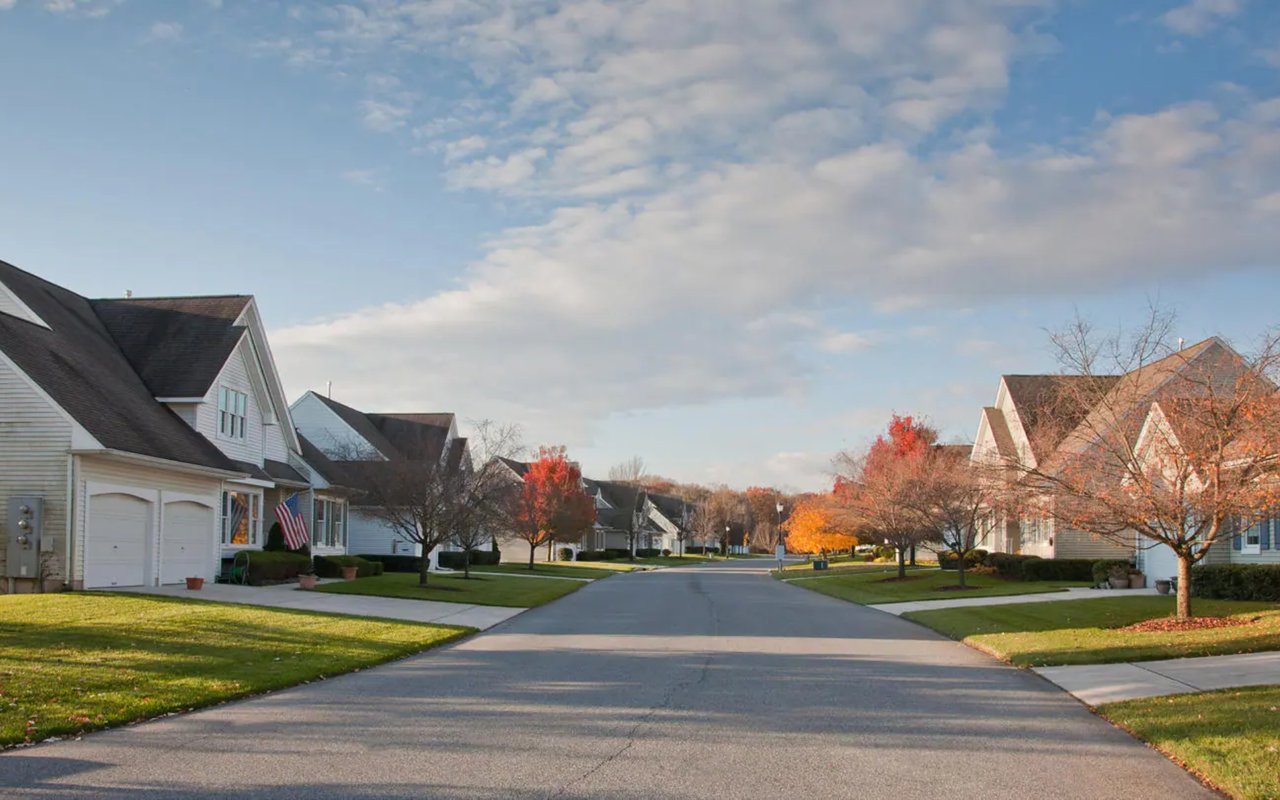 Residential street lined with detached homes and colorful autumn trees.
