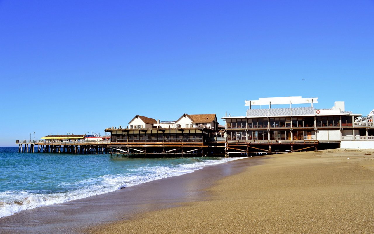 Beachfront pier buildings beside waves and sandy shore in South Redondo.