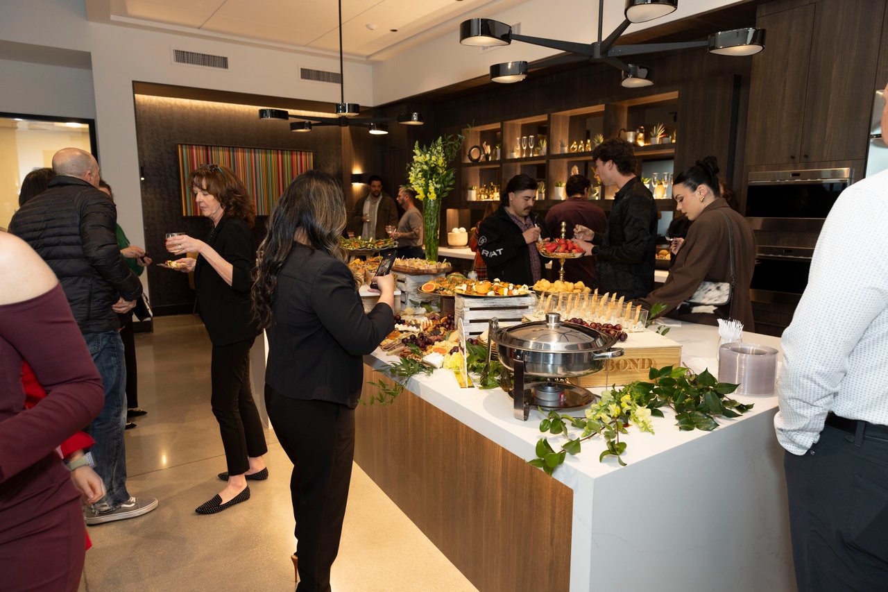 Guests mingle around a buffet at a client appreciation open house.