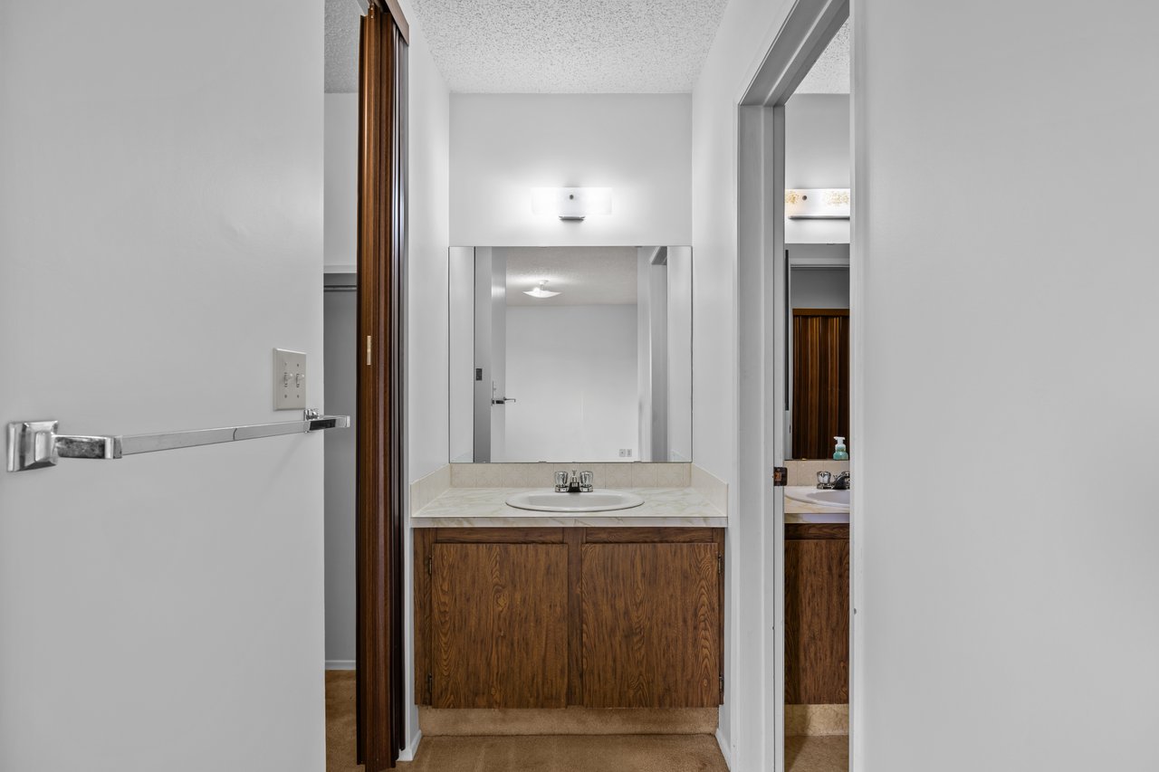 Bathroom vanity with a large mirror, oval sink, and dark wood cabinets.