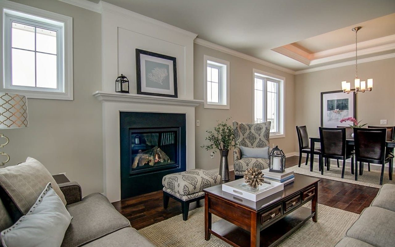 Living room with a gas fireplace and patterned armchair, opening into a dining area.