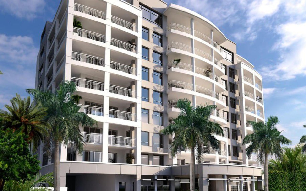 Modern condominium with curved balconies and palm trees along the street.