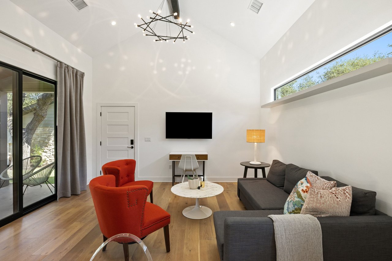 Living room with a charcoal sectional, red accent chairs, and sliding glass doors to a patio.