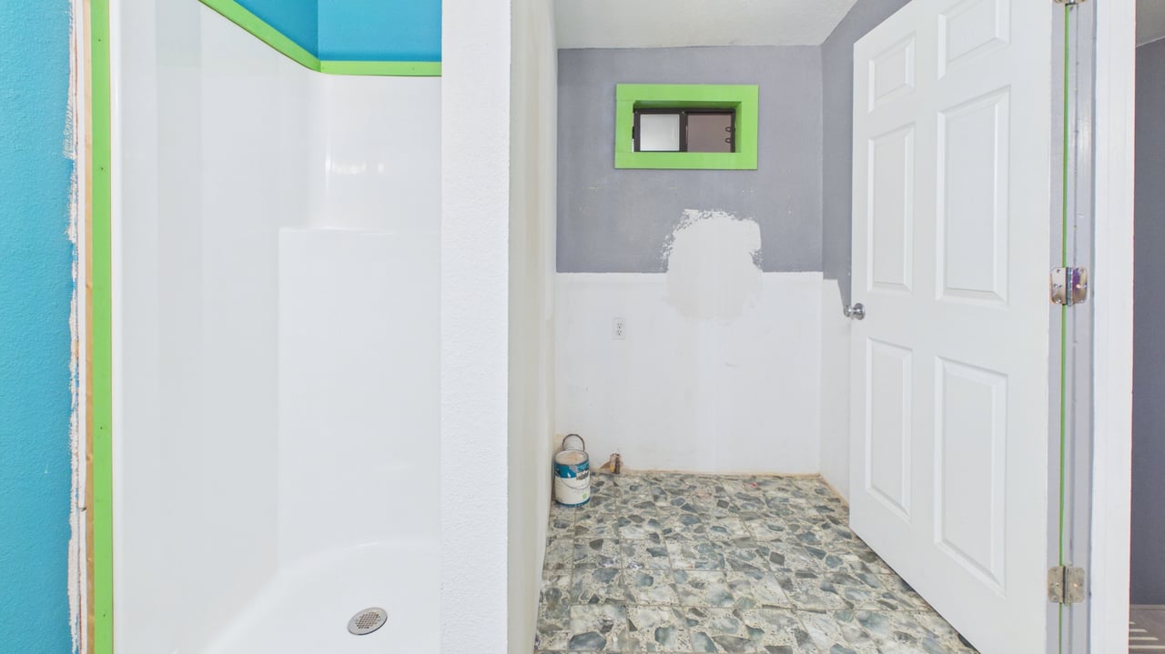 Bathroom with a white shower stall, patterned tile floor, and unfinished wall patch.