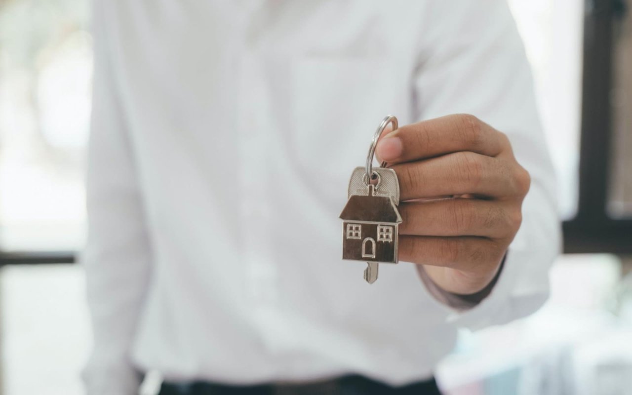 A man holding a key, indicating ownership or access to a home.