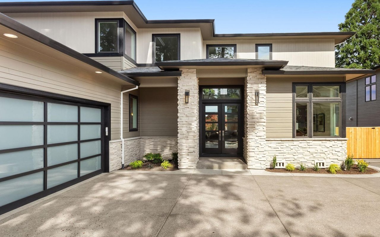 A modern house with a large garage door and a driveway.