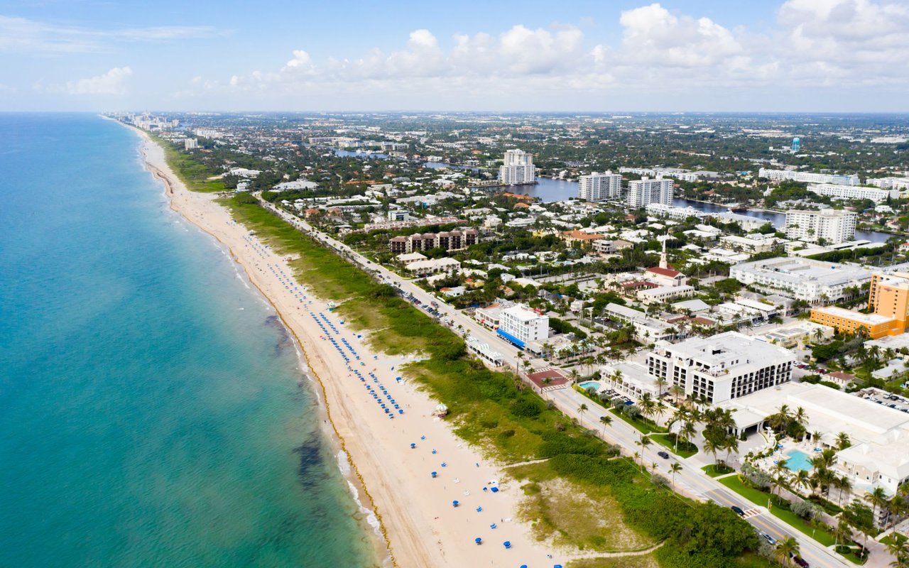 an aerial photo of a long white beach with blue waters in Delray Beach