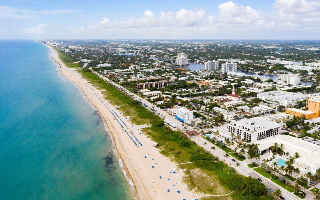 an aerial photo of a long white beach with blue waters in Delray Beach