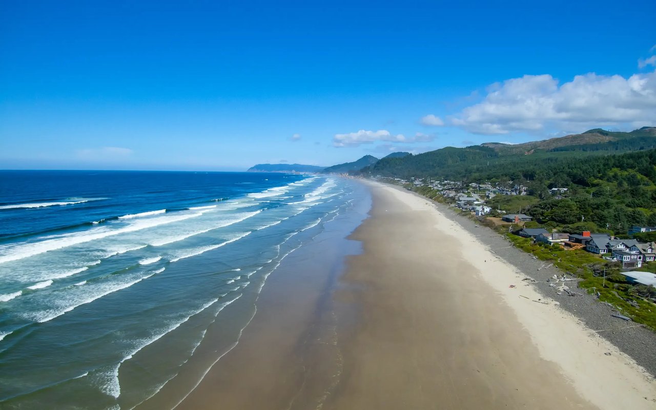 Arch Cape homes along the beach with a deep blue ocean and sky