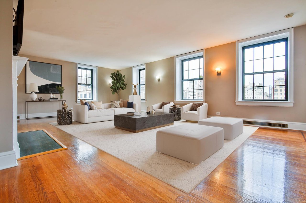 Living room with white seating, a dark stone coffee table, hardwood floors, and tall city-view windows.