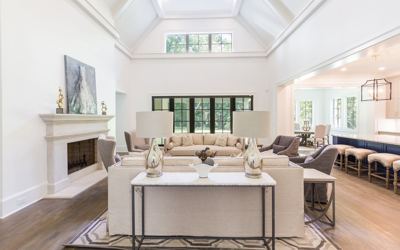 A living room with a white couch, black chairs, a fireplace, and a table