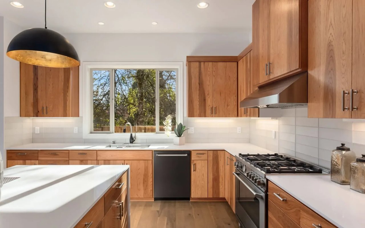 A modern kitchen with white quartz countertops, wood cabinets, and a large island with a breakfast bar.