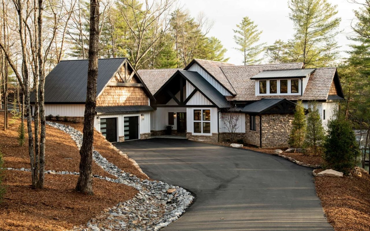  A large house with a long driveway surrounded by trees.