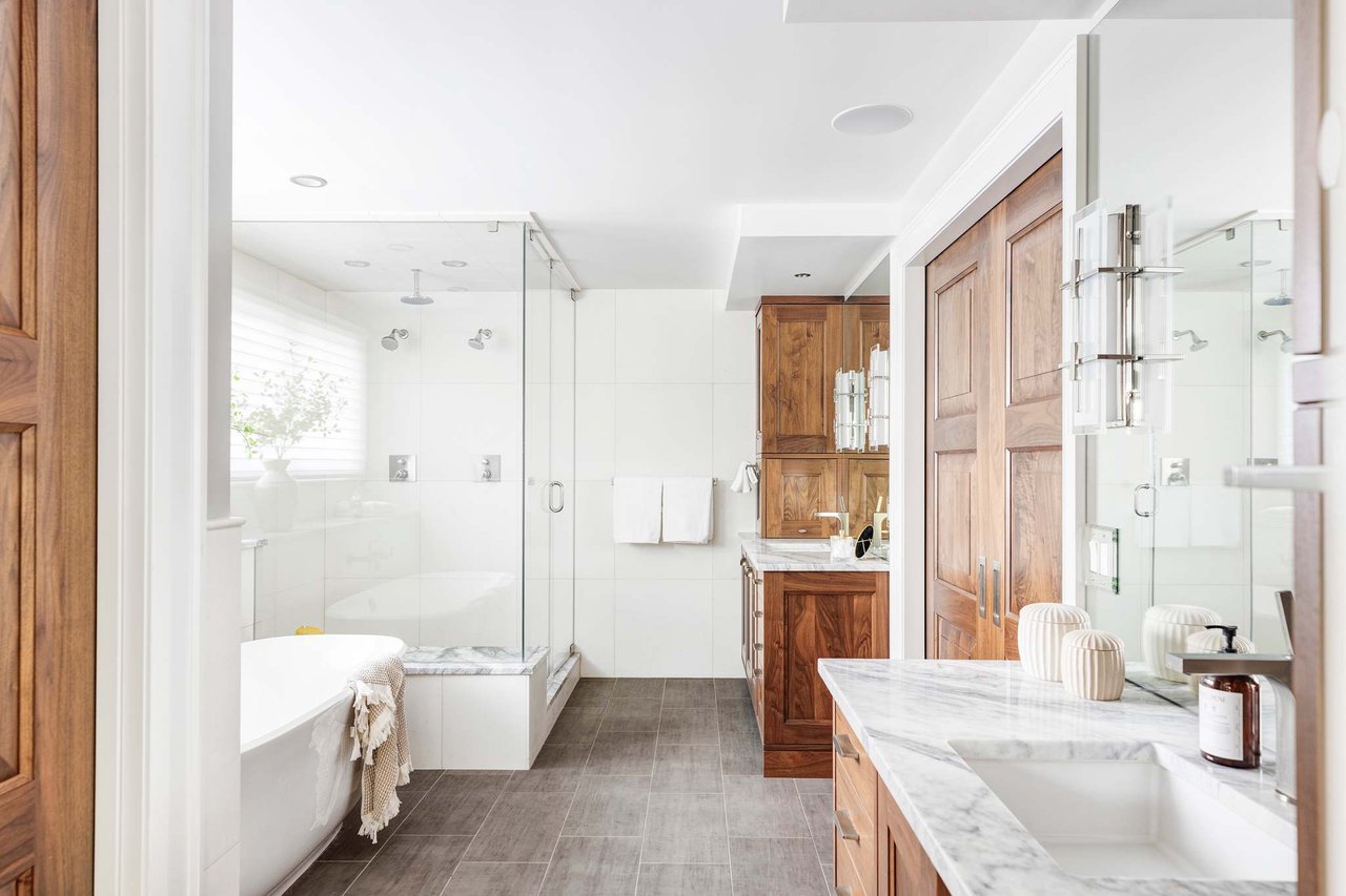 Luxury bathroom with walnut cabinets, marble counters, double shower, and freestanding tub