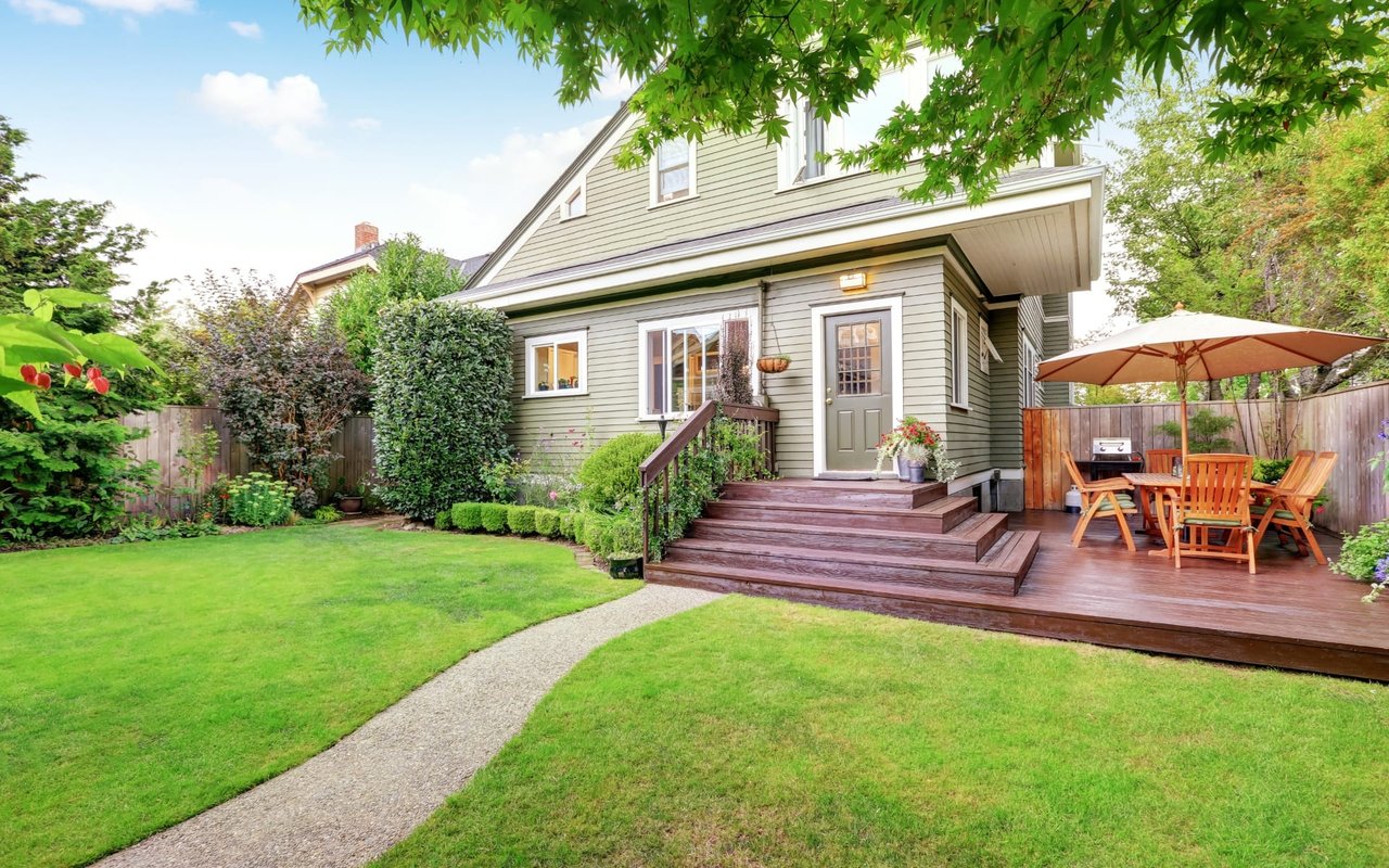 A two-story house with a wooden deck patio in front