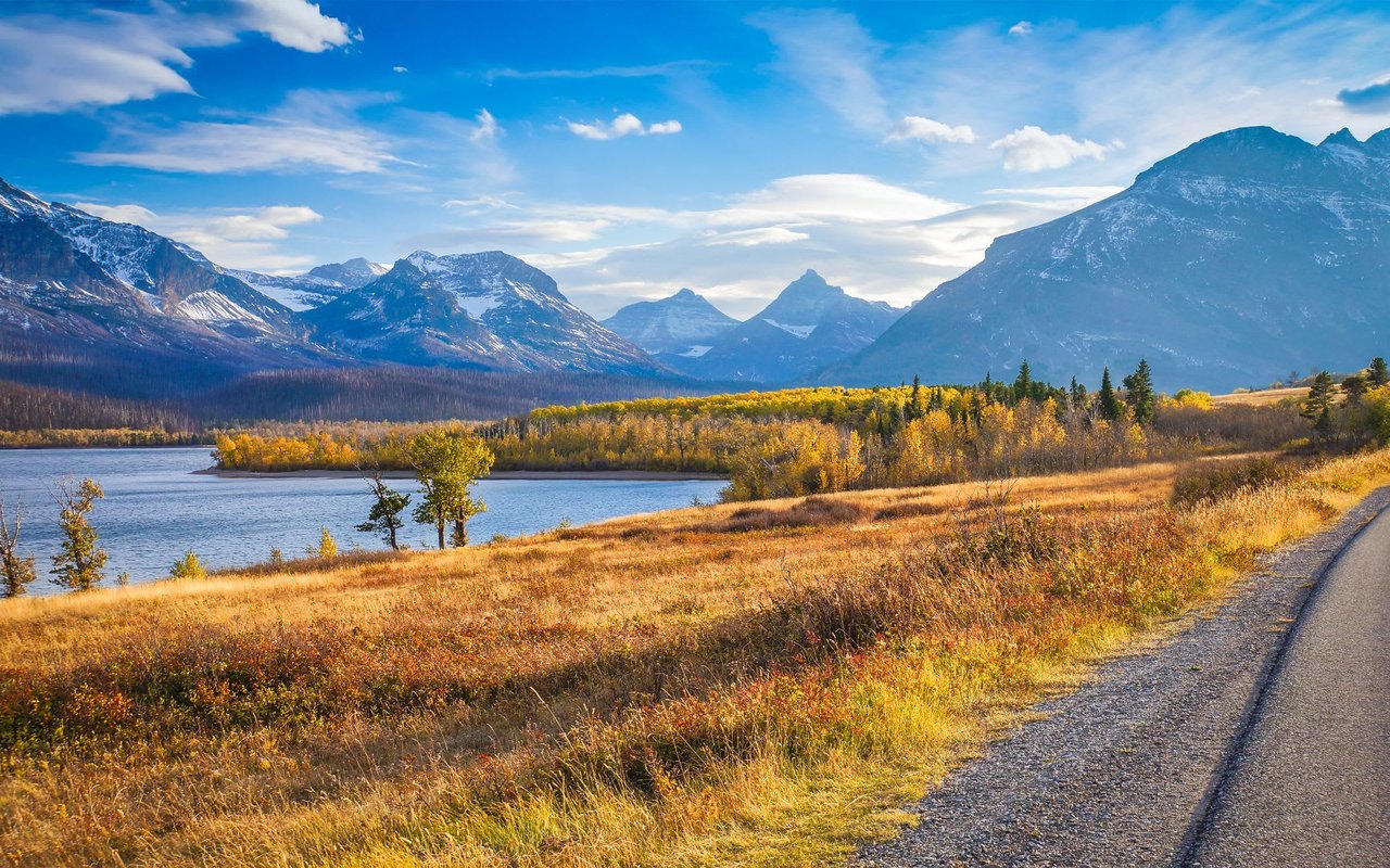  A stunning landscape view of a vast lake with calm, reflective water, bordered by fields of golden and reddish grasses