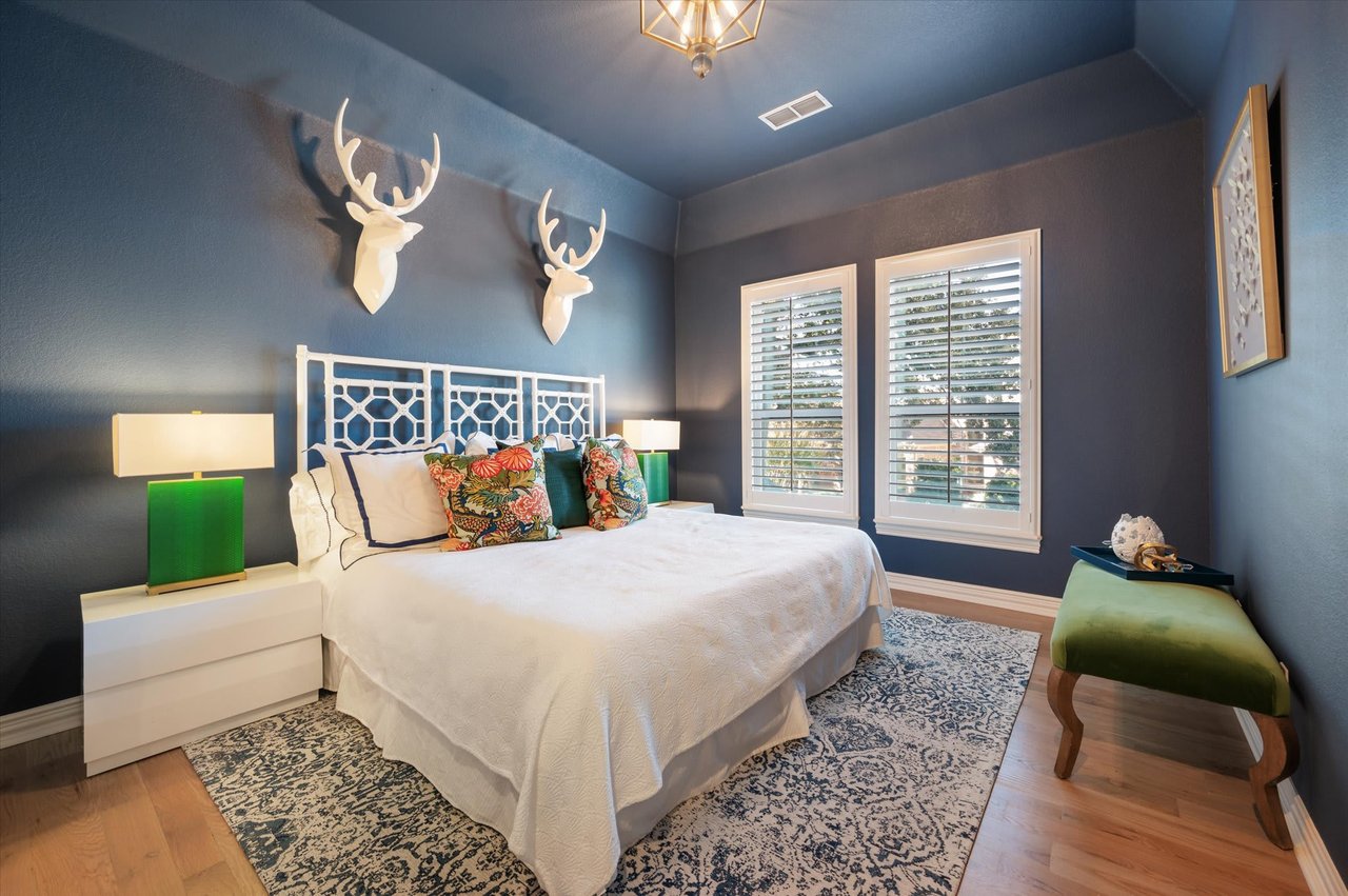 A cozy bedroom with a bed, two nightstands, and two deer heads on the wall