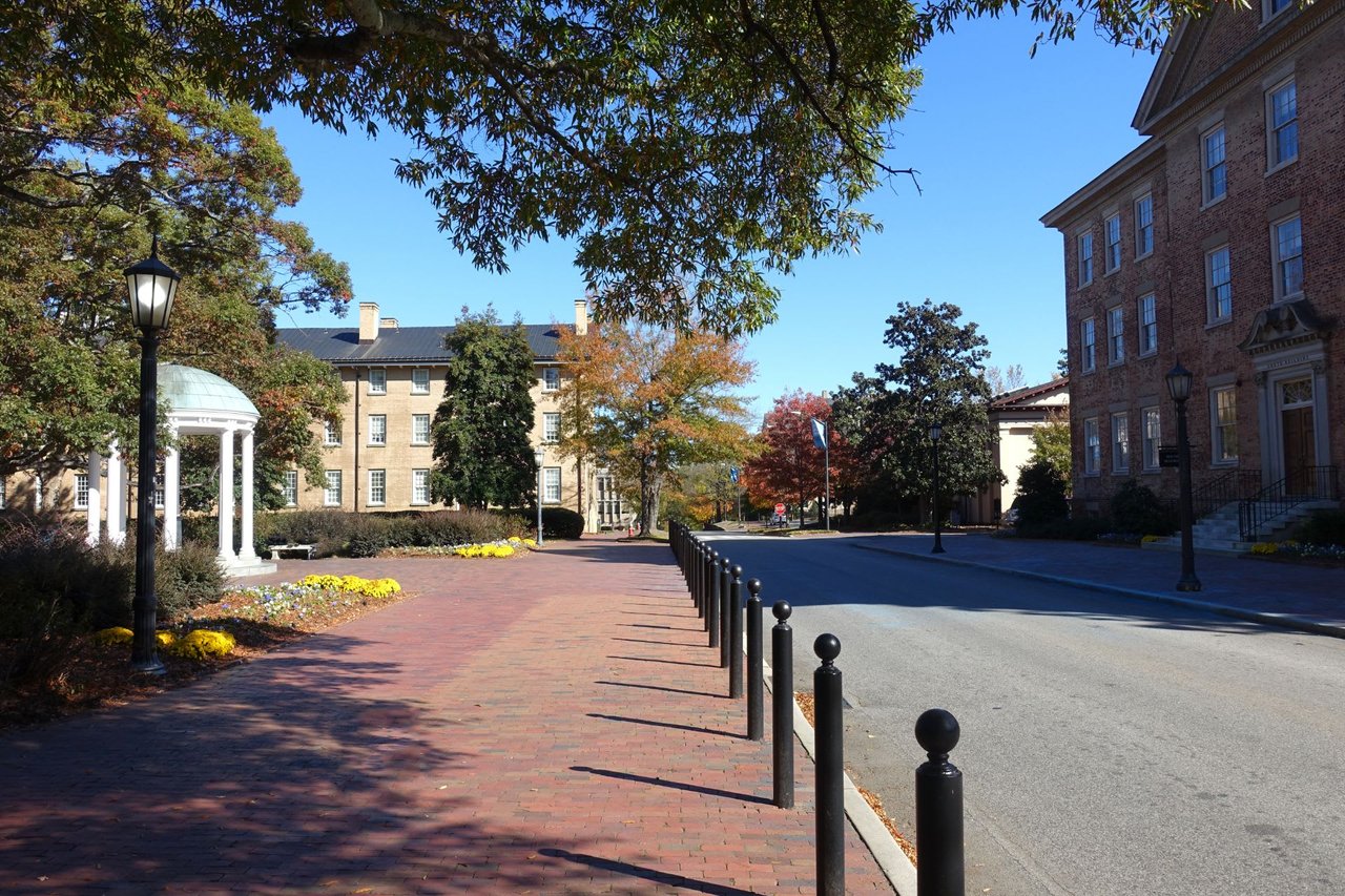 A brick sidewalk running alongside a row of metal poles.