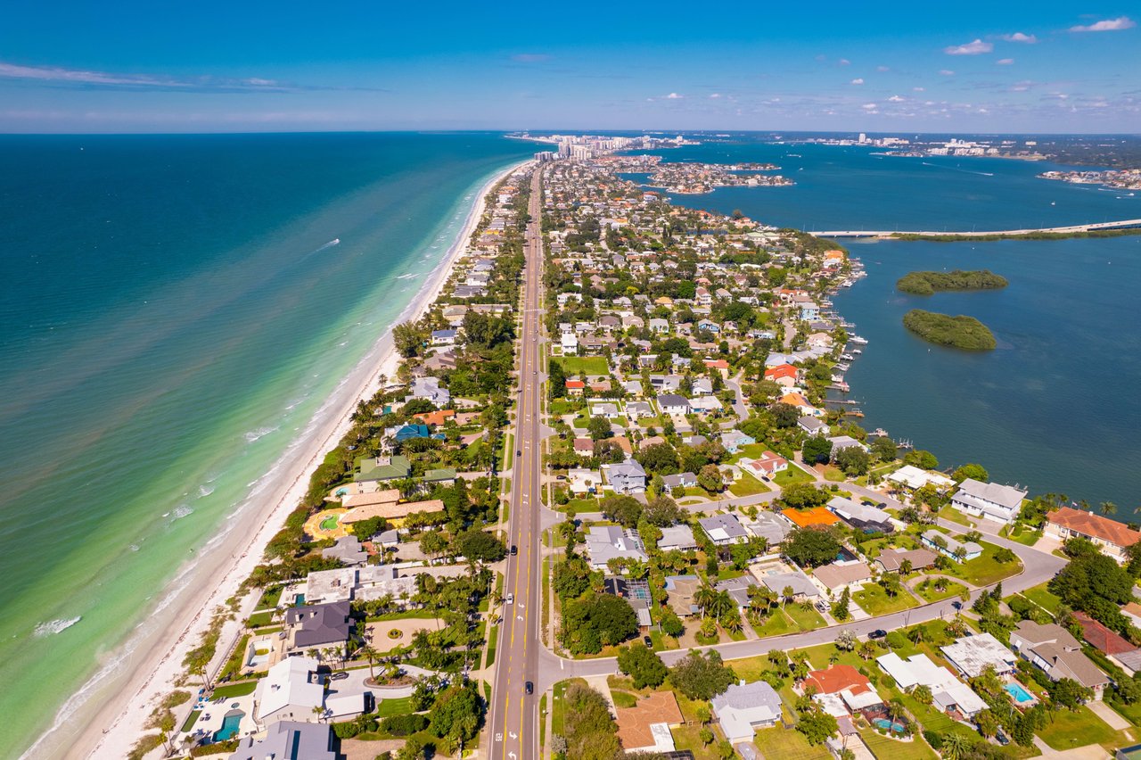 An aerial view of a long, narrow barrier island, likely Indian Rocks Beach or Fort Myers Beach in Florida