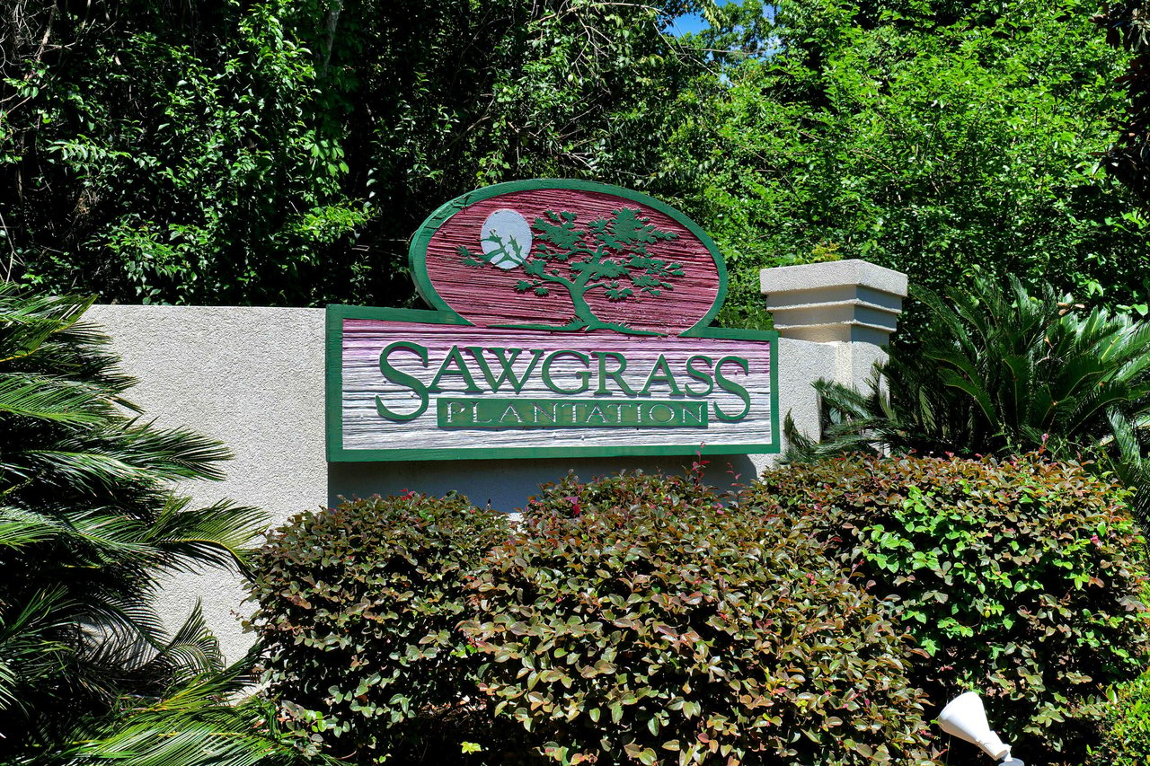 A ground-level view of a sign for "Sawgrass Plantation," indicating the entrance to another residential community.