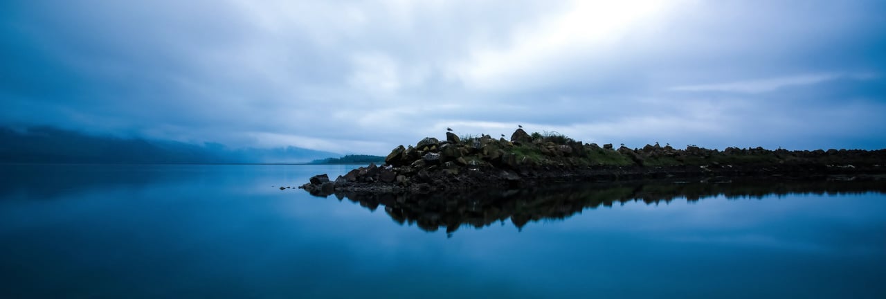 Netarts Oregon breakwater on an overcast day with a perfect reflection on the glassy water