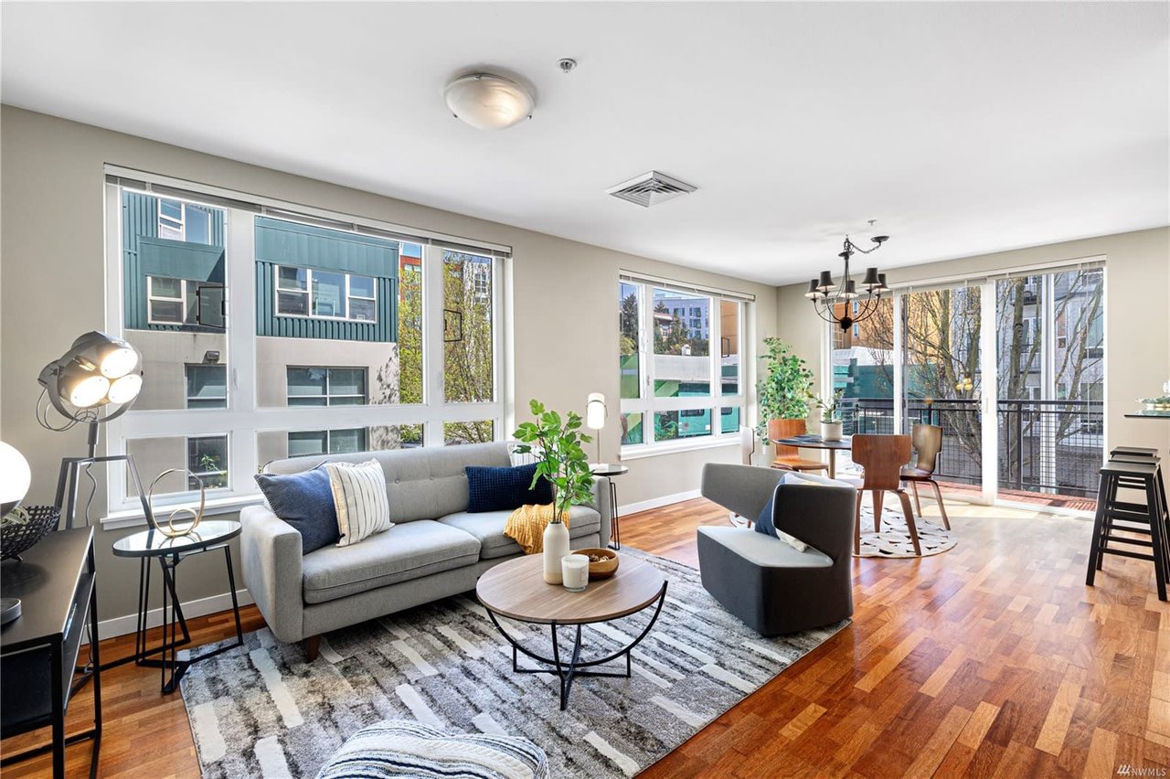 Chic and spacious condo living area with natural light, hardwood floors, and stylish furnishings.