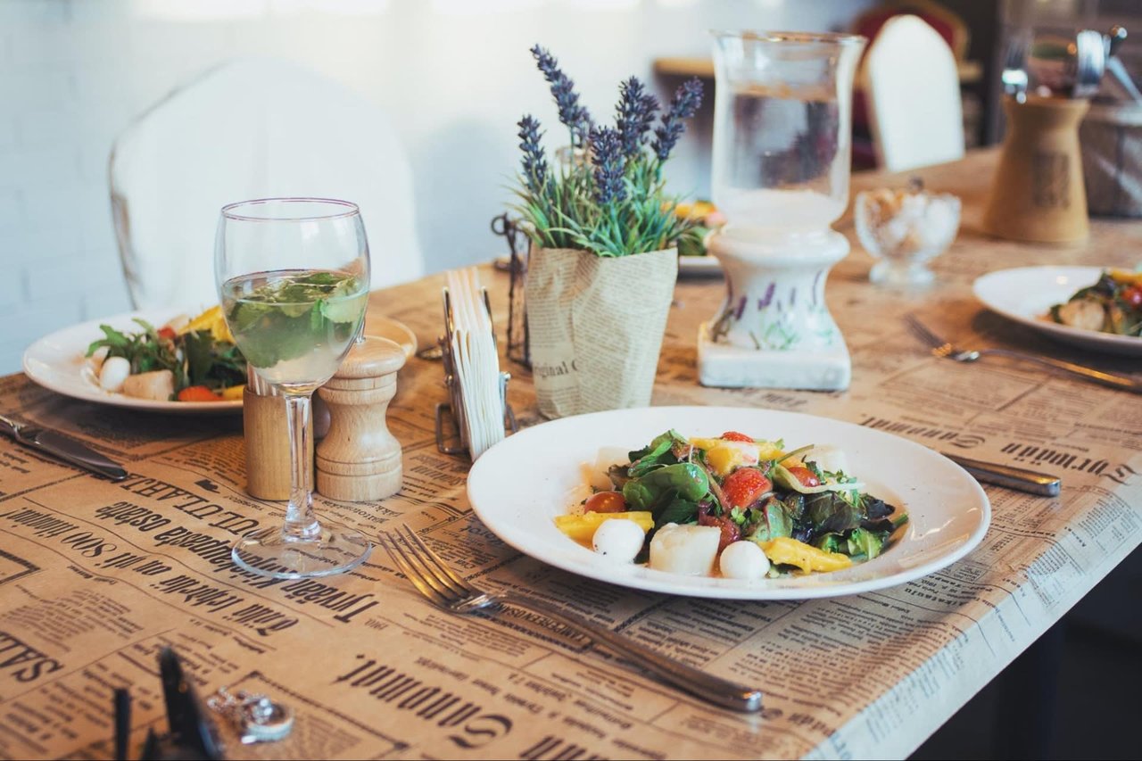  A close-up shot of a dining table set for a meal, featuring two plates of fresh salads with colorful ingredients like lettuce, tomatoes, and mozzarella balls.