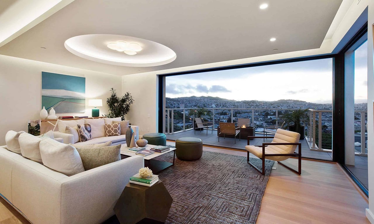 Modern living room with wall-to-wall sliding glass doors opening to a terrace overlooking San Francisco.