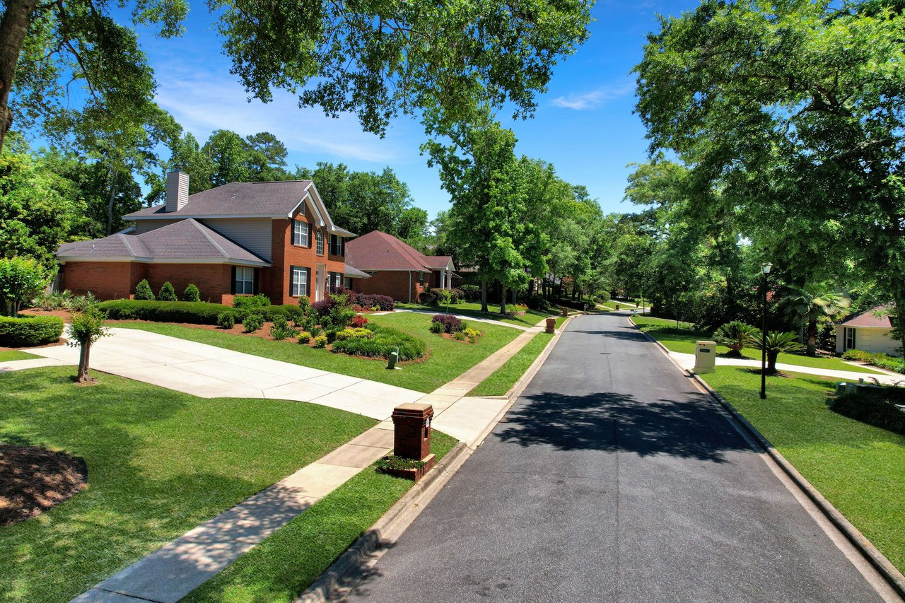 A ground-level view of a tree-lined street in a residential neighborhood in Tredington Park showing houses and well-maintained lawns.