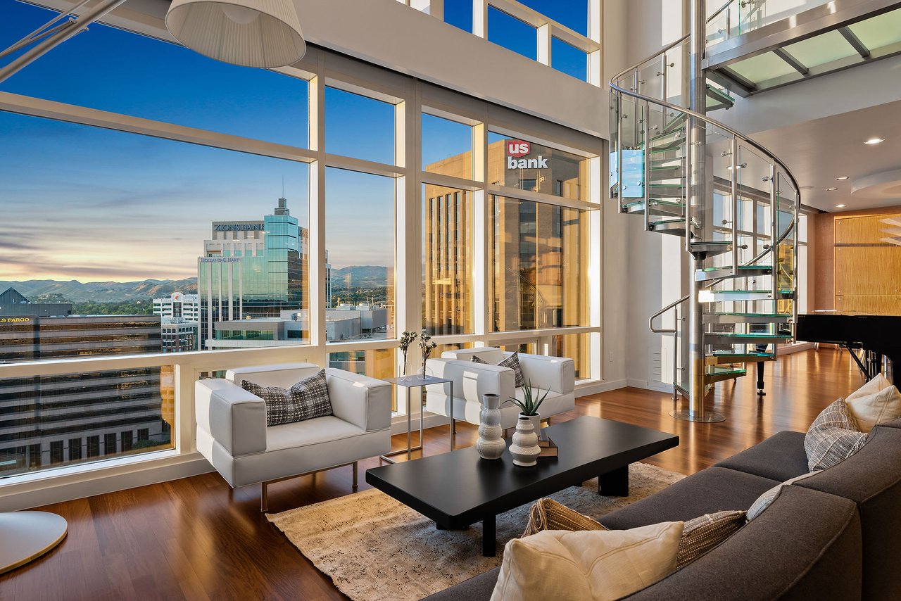  A spacious and modern penthouse living room, possibly in Charlotte, NC, featuring floor-to-ceiling windows that offer panoramic views of a city skyline