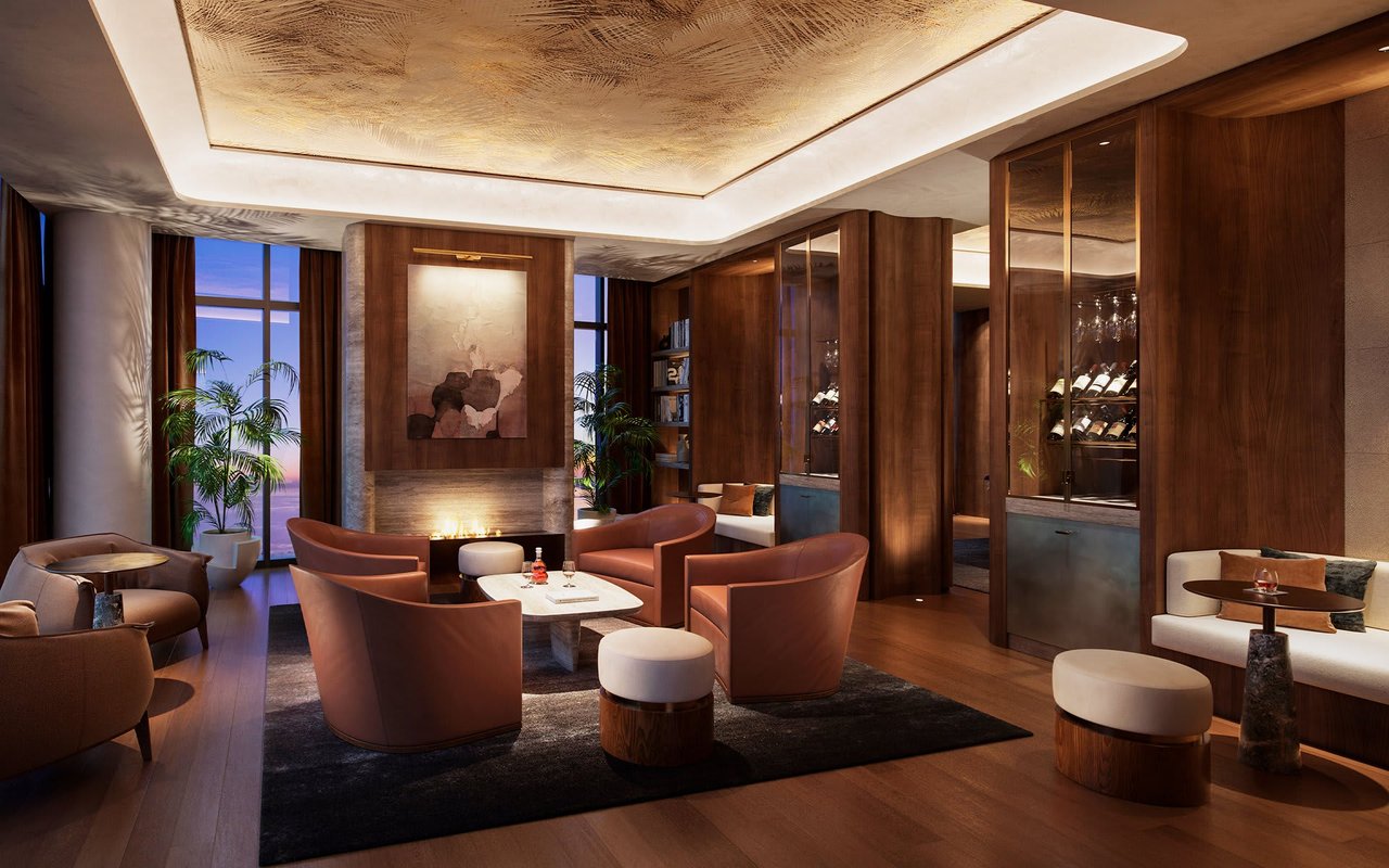 Furnished lounge with leather seating, a fireplace, and glass-fronted wine displays.
