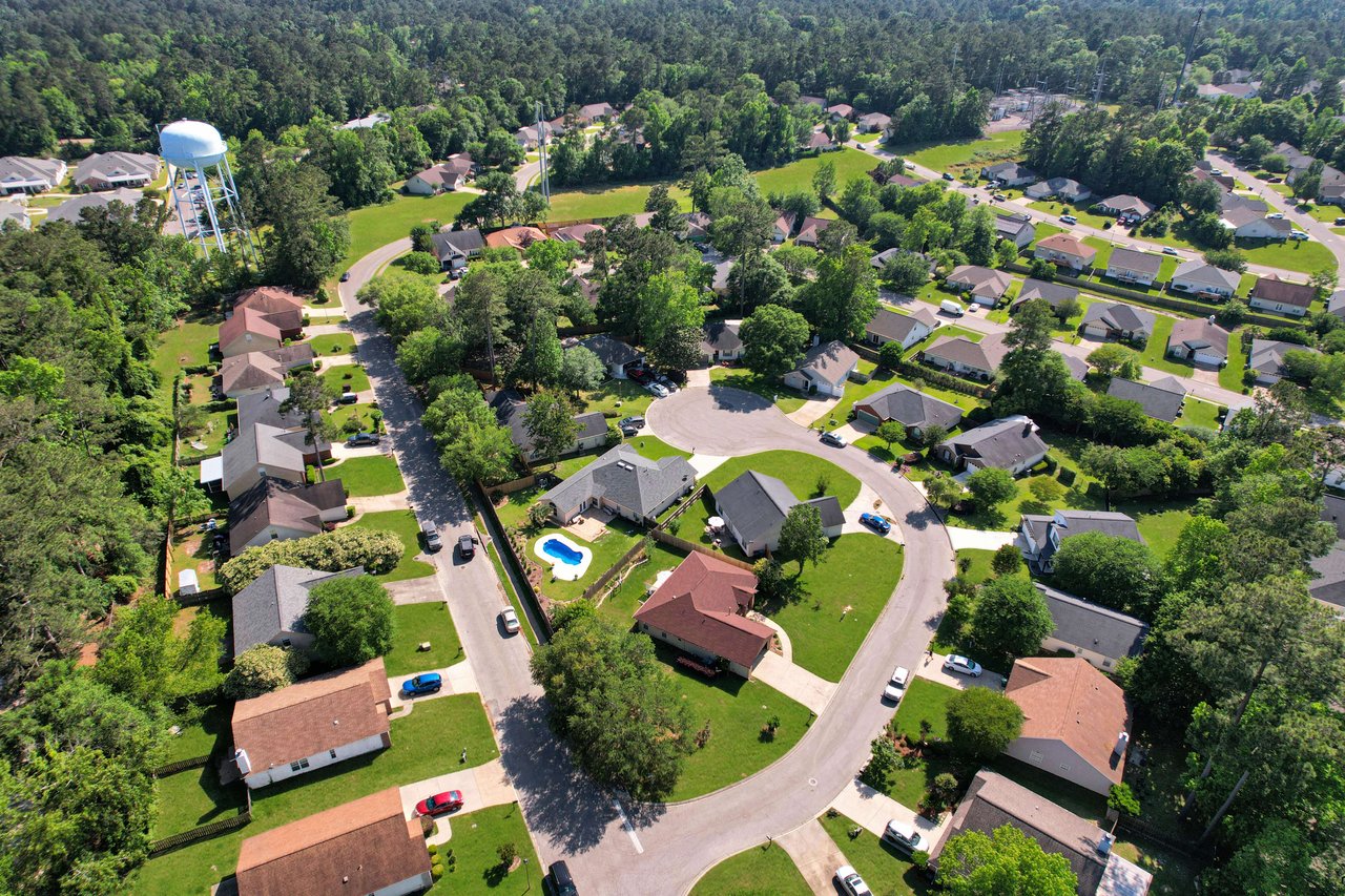 An aerial view of the Killearn Lakes neighborhood, showcasing the layout of houses, streets, and green spaces.