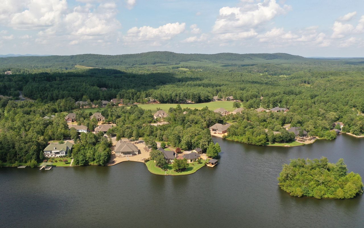 An aerial shot captures a sprawling residential community nestled around the shores of a large, dark blue lake
