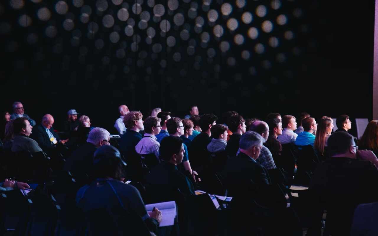  A tense, dimly lit room where people observe a person with rapt attention.