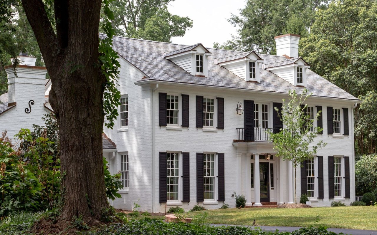 A white residential townhouse nestled among lush trees.