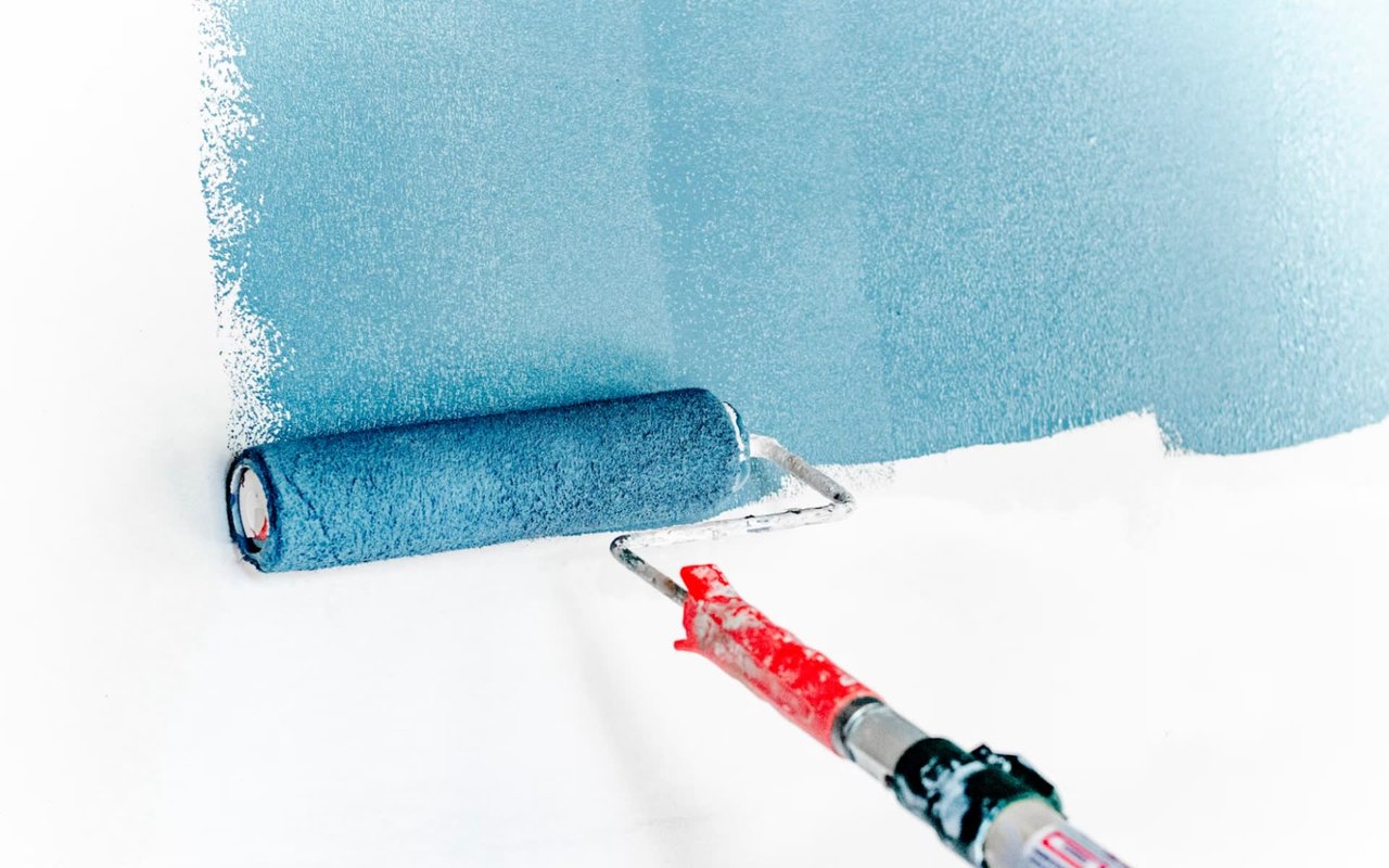 A white wall painted blue with a roller.