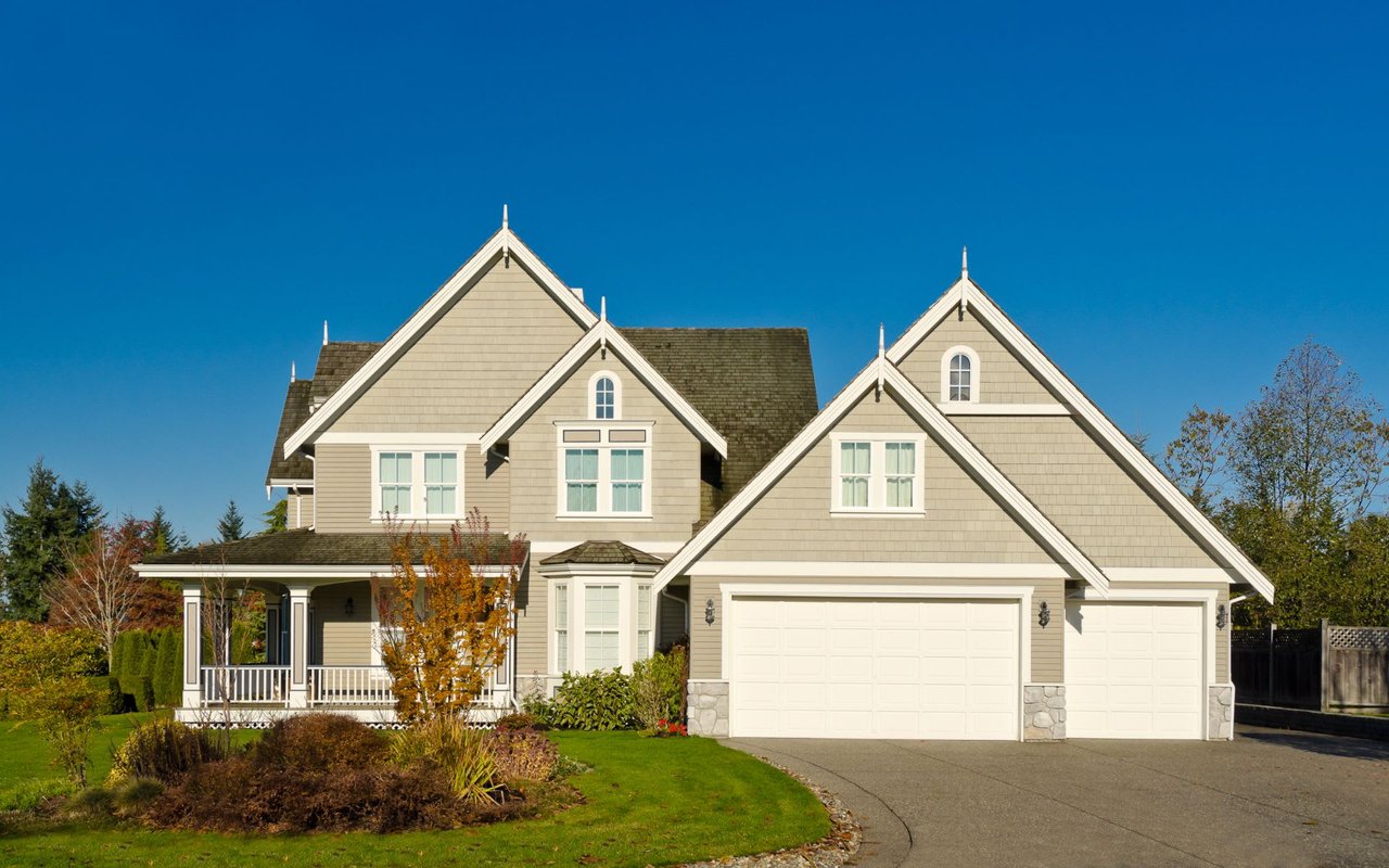 A large house with a white exterior, two car garages on the left side, and a covered porch on the front.