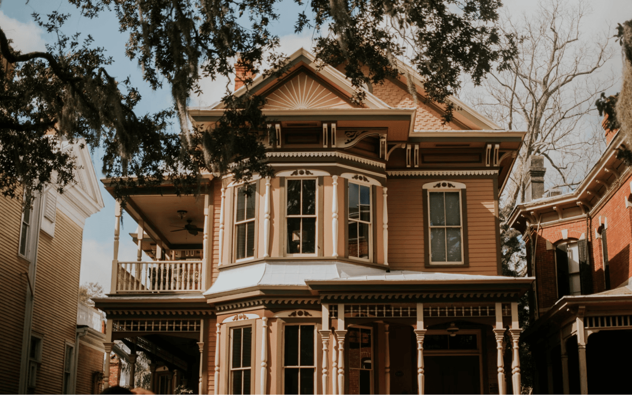  A grand Victorian-era house with intricate architectural details, predominantly in shades of brown and off-white trim.